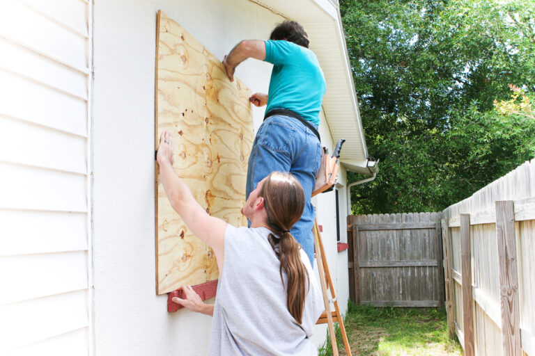 a family boards up windows before a hurricane